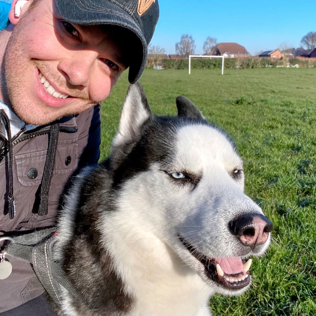 Photo of James Marshall with his dog Bailey in a park, smiling at the camera.