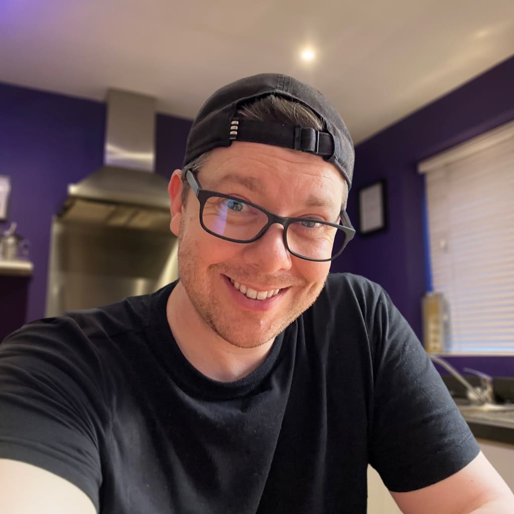 Photo of James Marshall in a kitchen, wearing a backwards baseball cap, smiling at the camera.